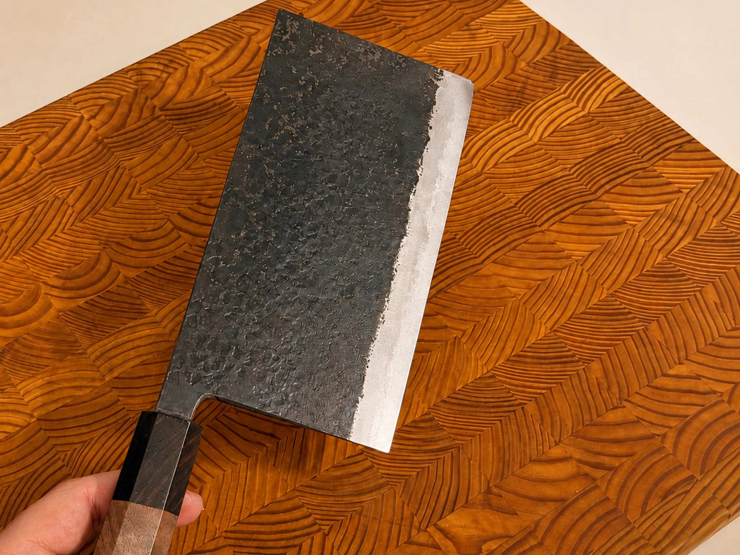 Hand holding a Moritaka Ishime mega nakiri over an end-grain wood cutting board