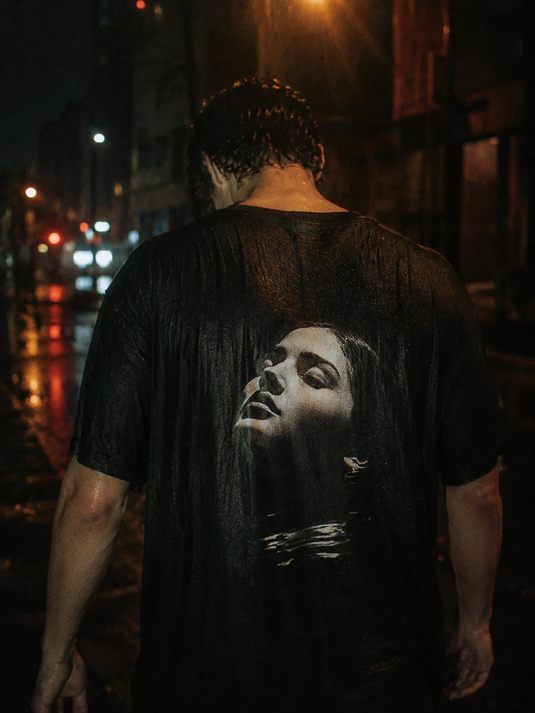 UNDERTOW tee worn down a rain-soaked night street, a woman's face surfacing from water printed on the back