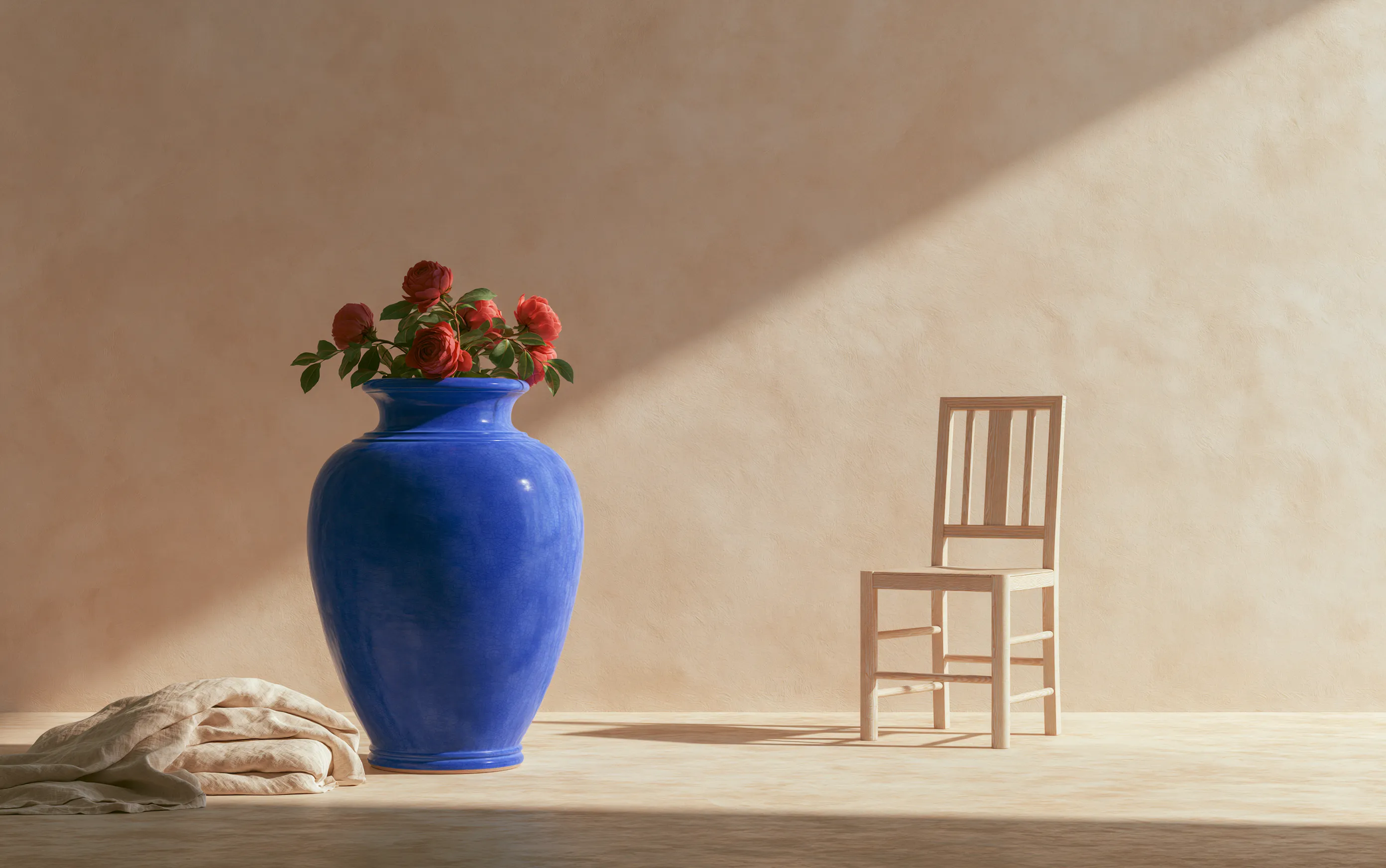 Cobalt ceramic vase, timber chair and folded linen in a sunlit studio
