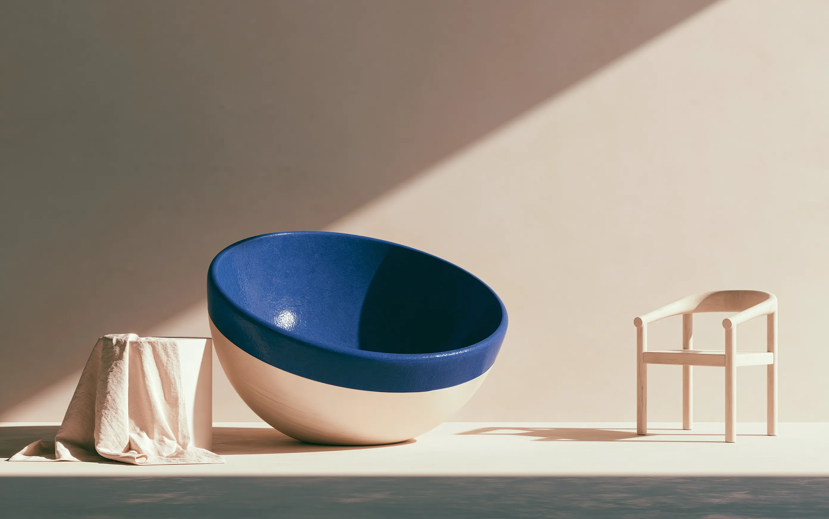 Large cobalt ceramic bowl and pale timber chair in a sunlit studio